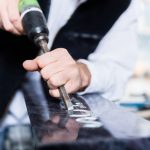 Craftsman working with pneumatic chisel at tombstone