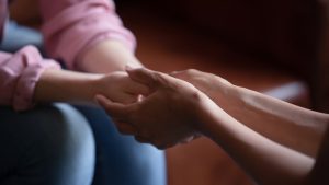 hands holding palms of millennial woman patient