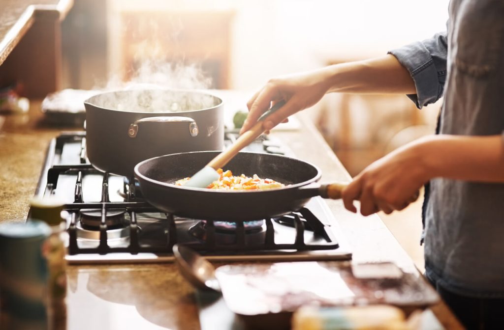 Hands cooking on a frying pan on a stovetop